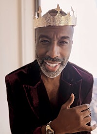 a black man wearing a crown in front of a window